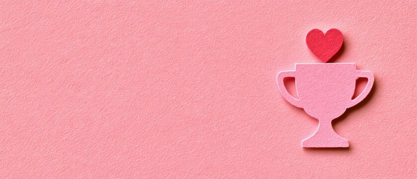 Pink trophy with heart on top on pink background symbolizing love success passion and achievement concept