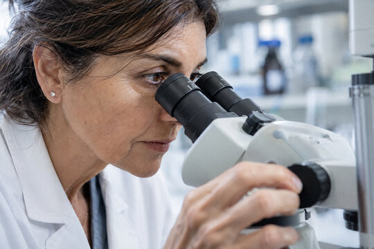 Mujer cient&iacute;fica trabajando con microscopio en un entorno de laboratorio
