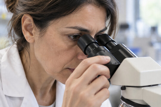 Mujer cient&iacute;fica trabajando con microscopio en un entorno de laboratorio