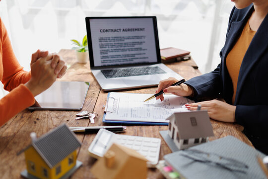 Real estate agent or broker discussing contract agreement terms and conditions with client, reviewing insurance papers for property purchase or mortgage loan application