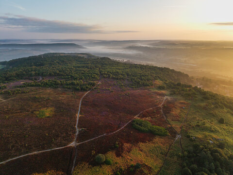 Beautiful drone landscape image over Stanton Moor in Summer Heather sunrise