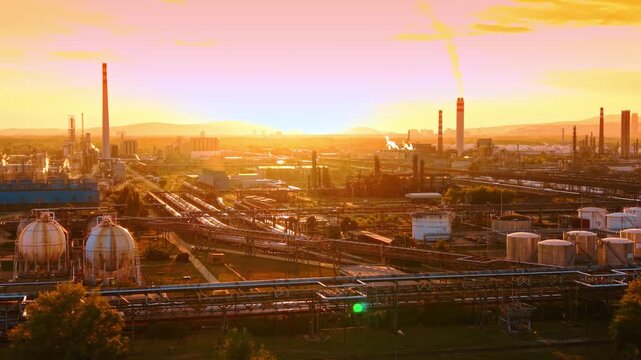 Spherical fuel storage tanks at an industrial refinery at sunset. White gas holders sit near metal pipe bridges in golden light.