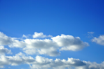 Obraz premium Bright blue sky with fluffy white clouds forming a natural cloudscape, creating a clean and peaceful outdoor background with ample copy space.