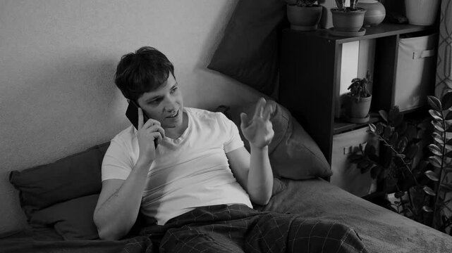 Young handsome guy uses mobile phone before sleep lying in bed and chatting with women to meet and seduce. Attractive man with the help of smartphone meets mistress and flirts