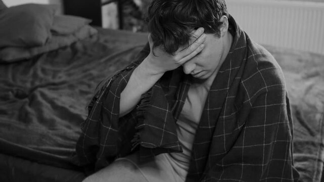 Sick guy with cold, flu or virus illness with cough and running nose lying in bed and using tissues. Sneezing ill guy at home. Man and health