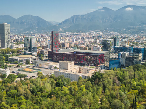 Albania, Tirana 06 09 2025: Close-up aerial drone photo focused on Arena stadium, Mother Teresa Square, Marriott and university with city center and cloudy mountains in background.