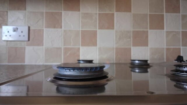 Slow motion view of a gas hob burner igniting with a blue flame, burning steadily, illustrating domestic gas consumption and energy use