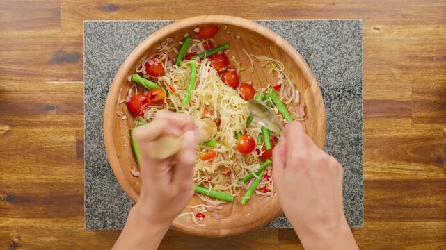 Pounding Green Papaya Salad in a Wooden Pestle and Mortar