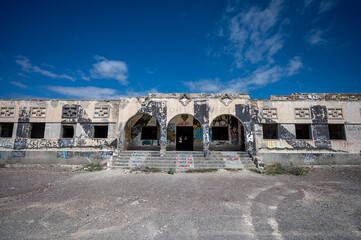 ABADES, TENERIFE, SPAIN - APRIL 24, 2025: Symmetrical main facade with arches and graffiti at the abandoned Sanatorio de Abona. © Peter