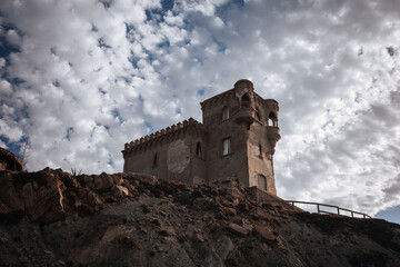 Old castle on a rocky hill with cloudy sky above during daylight hours © Bohdan