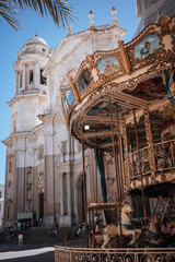 Historic carousel in front of a grand church in a sunny plaza on a clear day © Bohdan