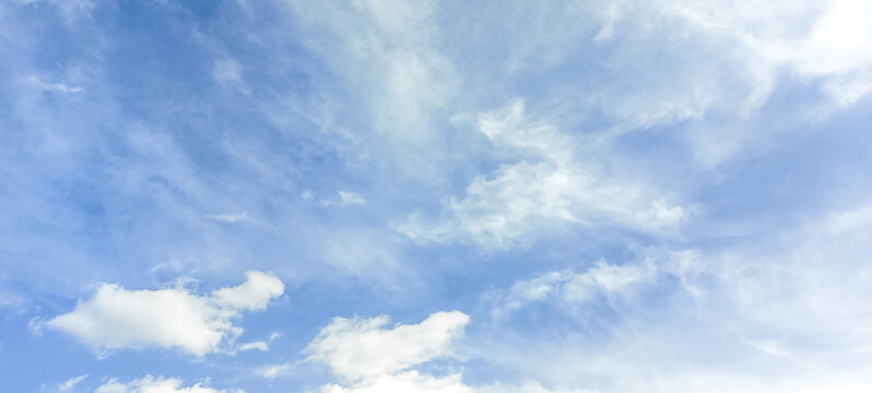 Clouds drift across the blue sky during the day in a clear atmosphere above a landscape