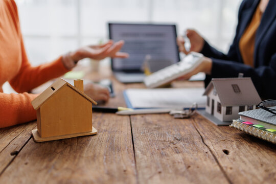 Real estate agent discussing home loan options and property investment plans with a client, calculating mortgage payments and analyzing financial documents for a new house purchase