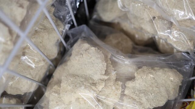 Frozen breaded food portions packed in clear plastic bags and stored in a freezer showing prepared food cold storage packaging preservation and bulk retail supply display