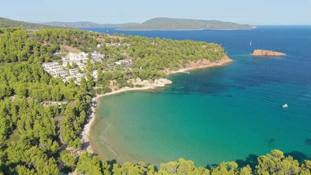 Aerial view of Chrisi Milia Beach on Alonnisos island, Northern Sporades, Greece. The coastline curves gently, with clear shallow water near the shore and deeper blue further out