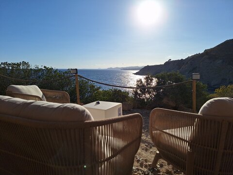Atardecer en una terraza de beach club con sillones de mimbre y vistas al mar Mediterr&aacute;neo
