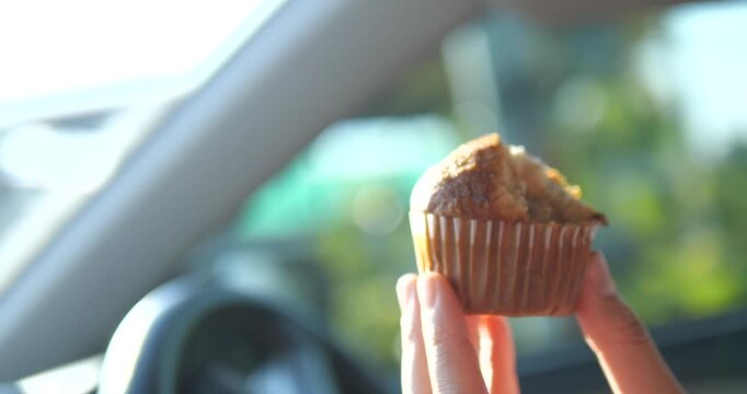 Close up of hand holding bitten banana muffin inside car