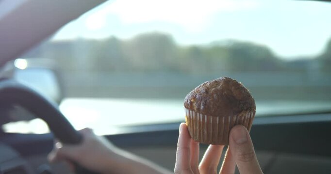 Close up of hand holding freshly baked banana muffin inside car