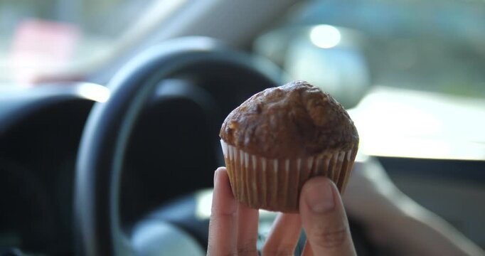 Close up of hand holding freshly baked banana muffin inside car