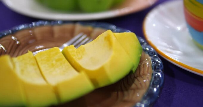Close up of ripe sliced fresh tropical fruit on plate with fork