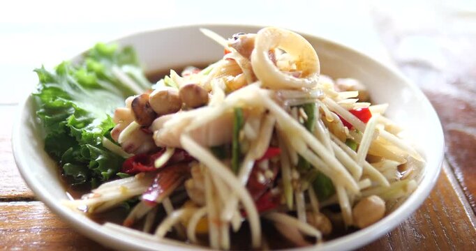 Close up of spicy Thai green papaya salad with boiled squid rings
