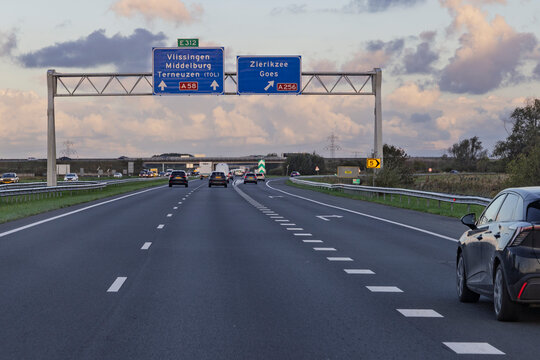 Zeeland, Netherlands, 16 September 2026. A black car driving in the foreground on the A58 motorway in the Netherlands, with overhead directional signs for Vlissingen and Zierikzee.