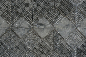 Obraz premium Dark gray natural stone wall cladding with a geometric checkered pattern and grooved surface, creating a modern architectural texture background