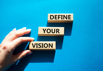 Concept words define your vision on wooden blocks arranged as steps. Businessman hand arranging wooden blocks. Strategic planning and goal setting concept. Blue background. Copy space. © Natallia