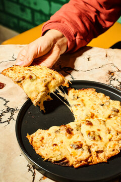 Hand pulling a cheesy mushroom pizza slice