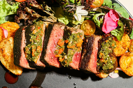Grilled beef steak with chimichurri sauce and roasted potatoes