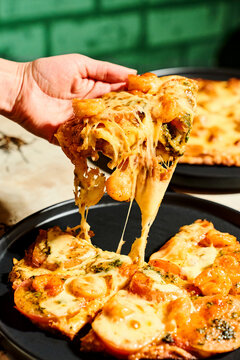 Hand lifting delicious shrimp pesto pizza slice with melted cheese