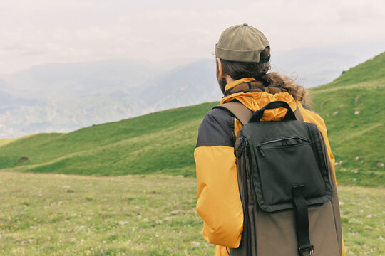 Hiker looks over green hills on a cloudy day