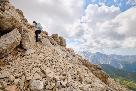 Active woman climbs the steep terrain in the Dolomites