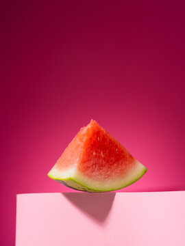 A juicy watermelon slice is perfectly positioned on a pink podium