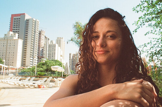 Woman with wet curly hair smiling at poolside