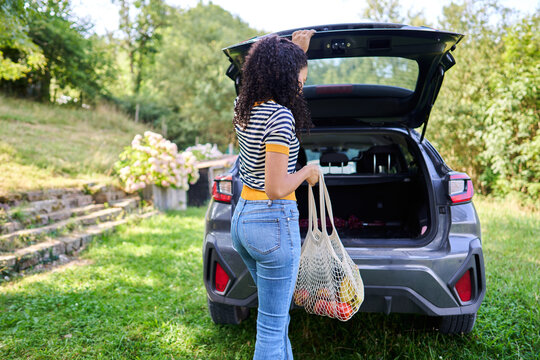 Woman unloading groceries from car trunk after shopping