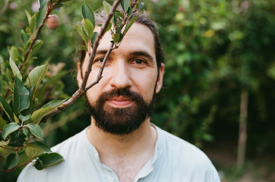 Man Stands Among Apple Trees in Orchard During Day