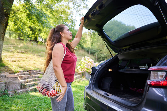 Woman opening car trunk with grocery bag