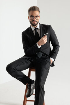 Confident man sitting on wooden stool posing
