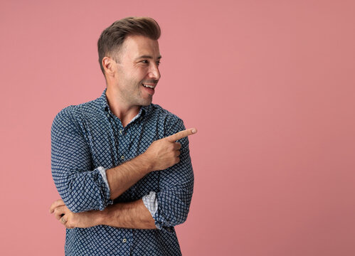 Joyful man pointing to side while smiling