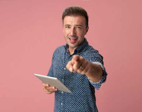 Cheerful man pointing while holding digital tablet