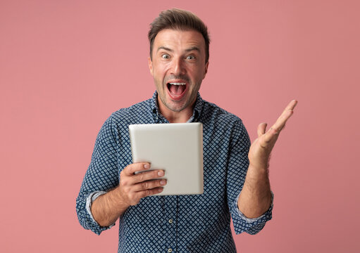 Amazed man holding digital tablet with raised hand
