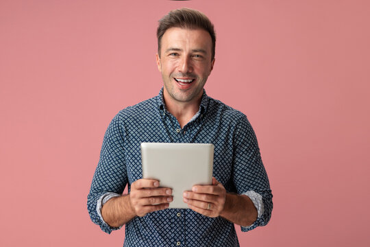 Cheerful man holding tablet looking forward