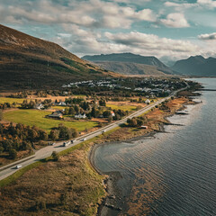 Vertical aerial view of a scenic coastal road winding past a village and mountains along the ocean in northern Norway with copy space in sky © Quality by Simon