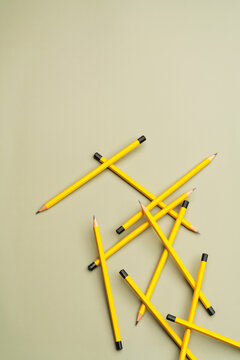 Scattered yellow pencils on oil green background