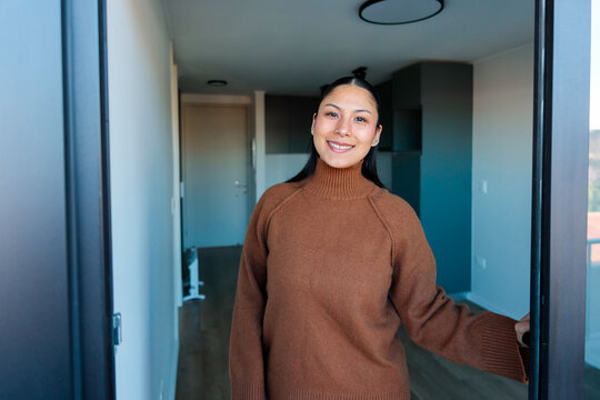 Woman smiling near open apartment balcony