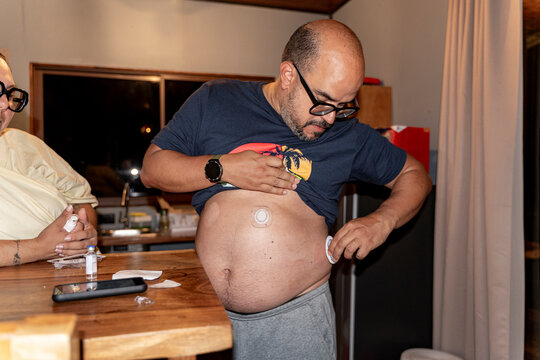 Individual applying continuous glucose monitor to abdomen