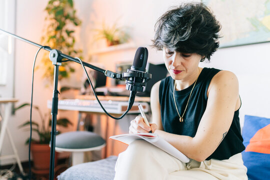 Woman writing lyrics in home music studio