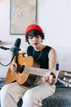 Woman playing acoustic guitar and singing in home studio