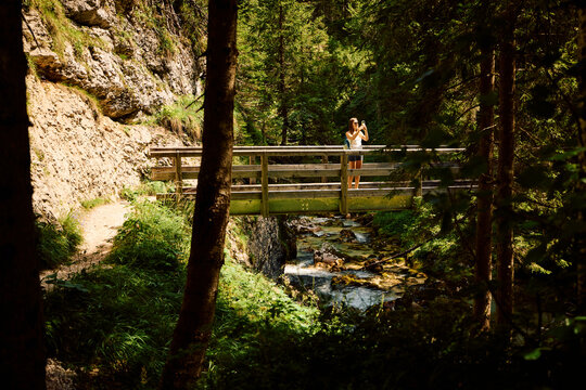 Woman snaps photos on a wooden bridge in the mountain